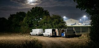 Nocna scena przy bazie RAF Fairford. Trzy białe furgonetki z otwartymi drzwiami i beczkami w środku, zaparkowane przy miedzy. Słowo kluczowe: rolniczka udaremnia zamach.